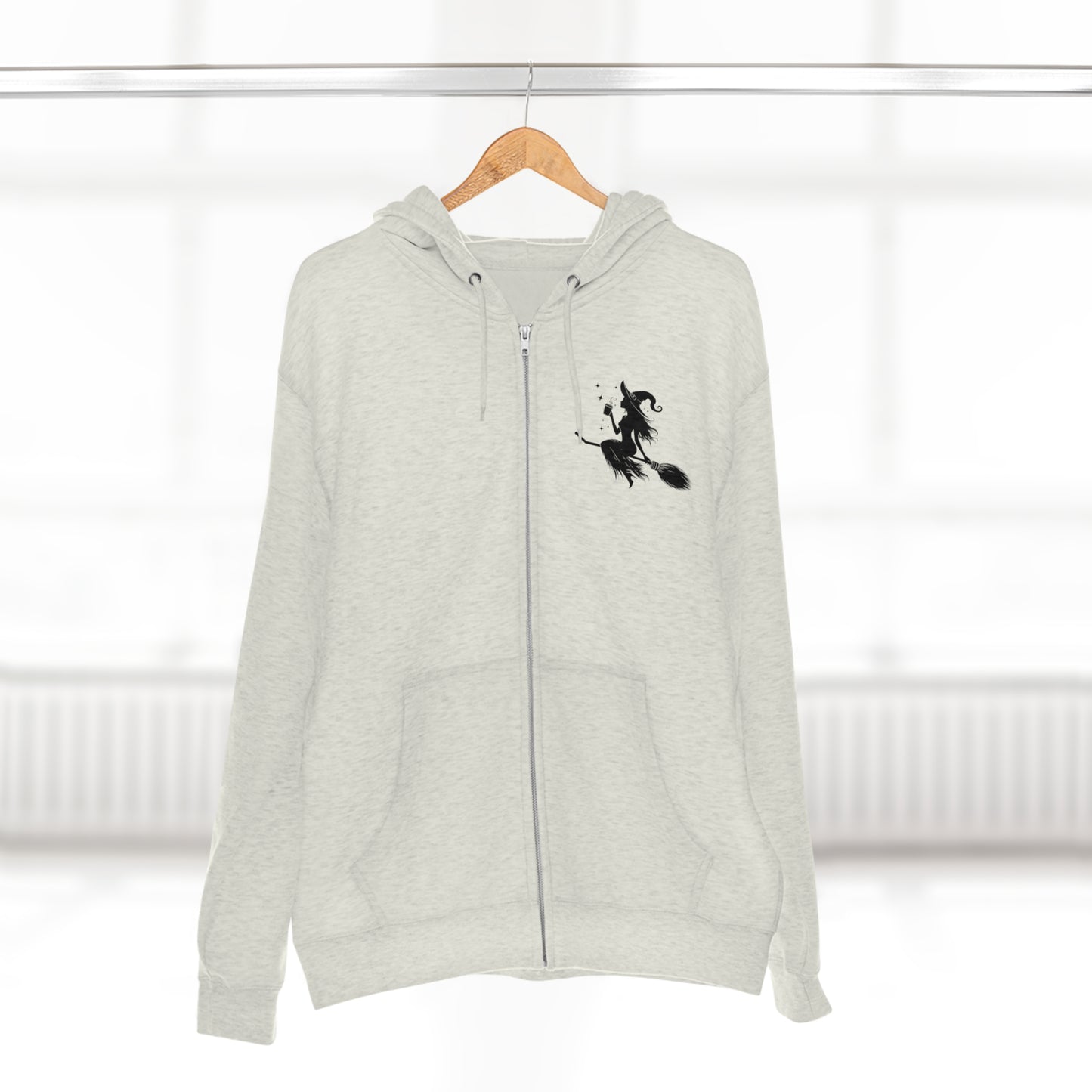 Hoodie: featuring a witch flying with a coffee cup, with a moon in the background. Oatmeal color Hoodie with Black graphics on the front chest, and back.